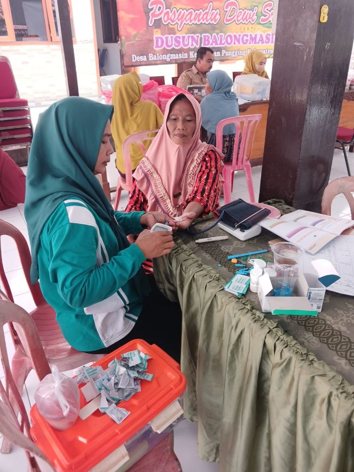 MELAYANI: Salah satu kader sedang mengecek tekanan darah salah satu lansia di Dusun Balongmasin, kemarin (12/11)