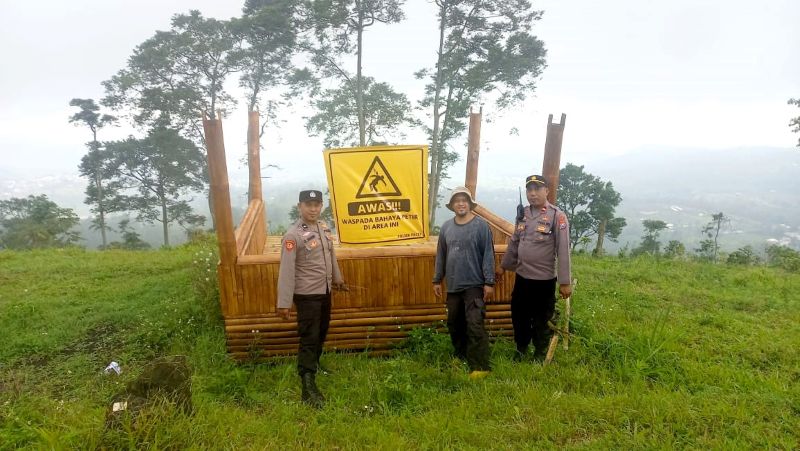 ANTISIPASI: Petugas kepolisian memasang spanduk imbauan bahaya tersambar petir di Bukit Bodoh Gede, Desa Padusan, Kec amatan Pacet.