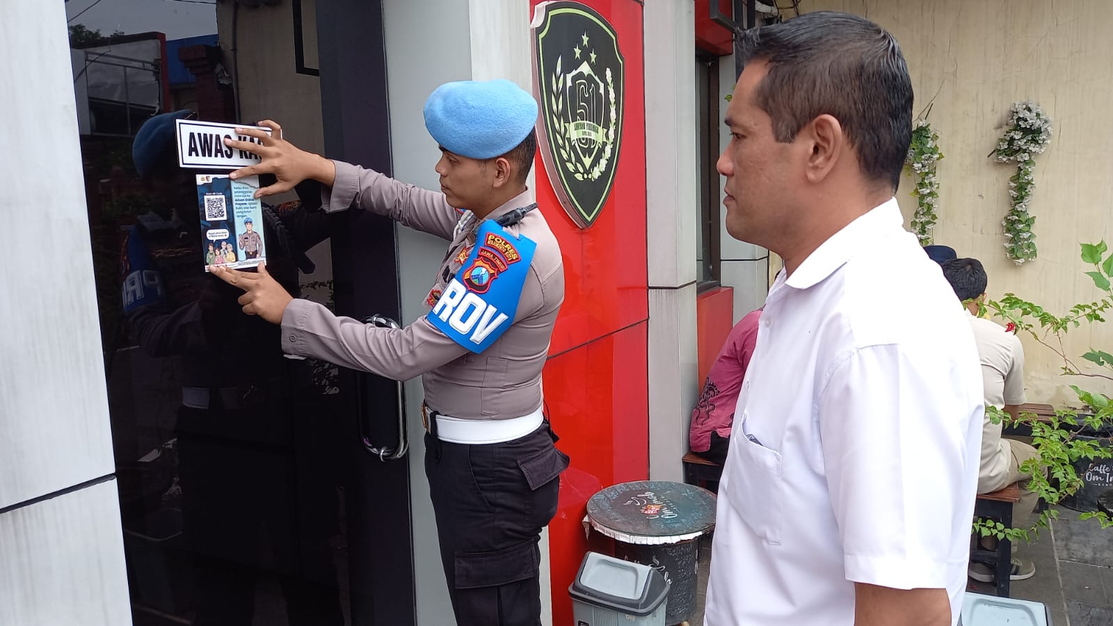 JEMPUT BOLA: Propam Polres Mojokerto Kota memasang stiker barcode pelaporan di Mapolres Kota Mojokerto, Kamis (13/11).