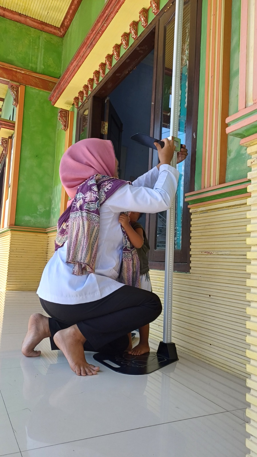 PELAYANAN: Kader posyandu sedang mengukur tinggi badan seorang balita di Ponkendes Desa Jiyu.