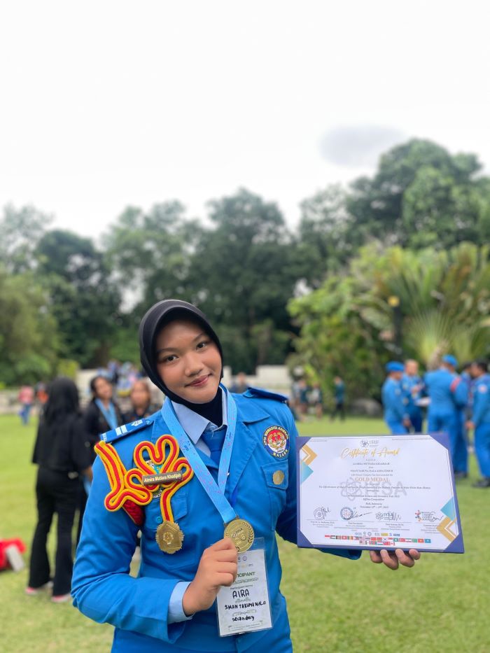 SENANG: Almira Mutiara Khadijah memegang piala emas saat di event bergengsi International Science Invention Fair (ISIF) di Bali.
