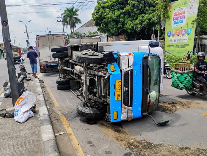 MELINTANG: Truk boks muatan ayam beku terguling usai menghantam median dan traffic light di simpang tiga Jalan Raya Desa Lengkong, Kecamatan Trowulan, kemarin (22/11).