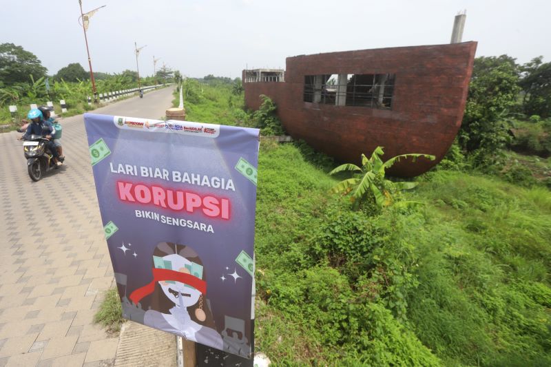 IRONI: Poster kampanye antikorupsi sisa event Hakordia Run Minggu (23/11) masih terpasang di area proyek kapal Taman Bahari Mojopahit (TBM). Proyek itu tengah berperkara di Pengadilan Tipikor Surabaya