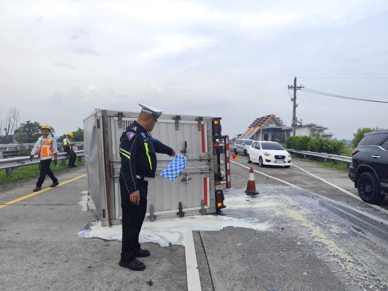 MELINTANG: Truk boks nopol L 8245 DAA terguling usai mengalami pecah ban di ruas tol Jomo KM 711/400 jalur B, Jumat (28/11) sore.