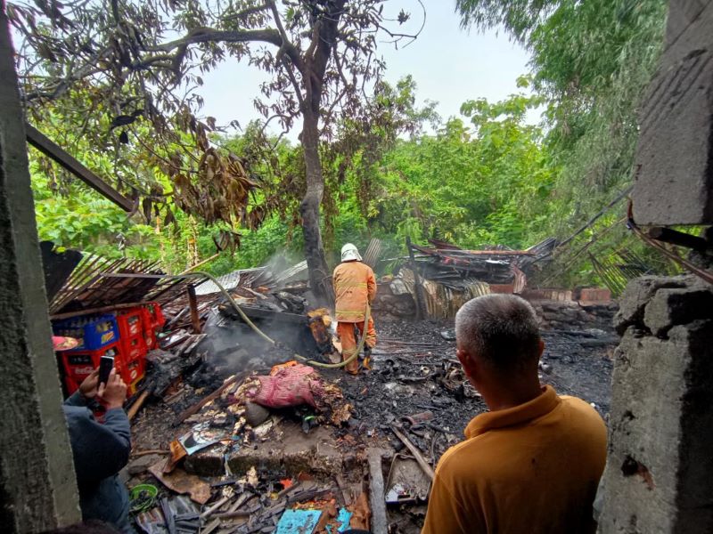 DIPADAMKAN: Petugas melakukan pembasahan gudang rongsokan di Desa/Kecamatan Dawarblandong yang ludes terbakar, Senin (1/12).