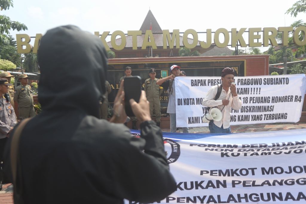 SAMPAIKAN ASPIRASI: Tiga pegawai honorer yang diputus kontrak berdemo di depan Balai Kota Mojokerto, kemarin (8/12). (Foto kanan) Peserta demo membentangkan poster protes.