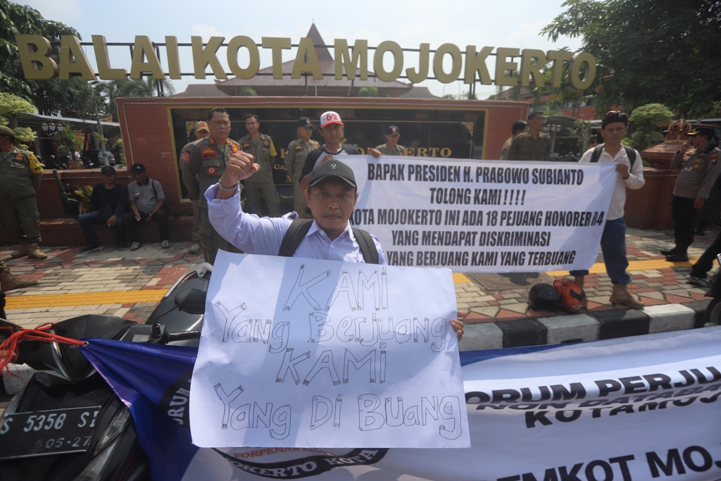 SAMPAIKAN ASPIRASI: Tiga pegawai honorer yang diputus kontrak berdemo di depan Balai Kota Mojokerto, kemarin (8/12). (Foto kanan) Peserta demo membentangkan poster protes.