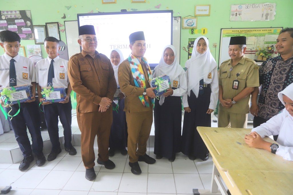 PEDULI PENDIDIKAN: Bupati Muhammad Albarraa secara simbolis menyerahkan paket seragam gratis kepada siswa SDN Banjaragung 1 dan SMPN 1 Sooko, kemarin (8/12).
