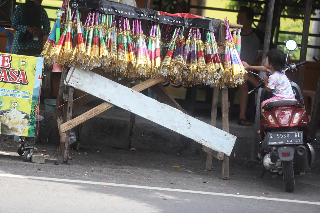 JELANG NATARU: Seorang anak mencoba meraih terompet yang dijajakan di Jalan Surodinawan, Kota Mojokerto, Selasa (9/12).