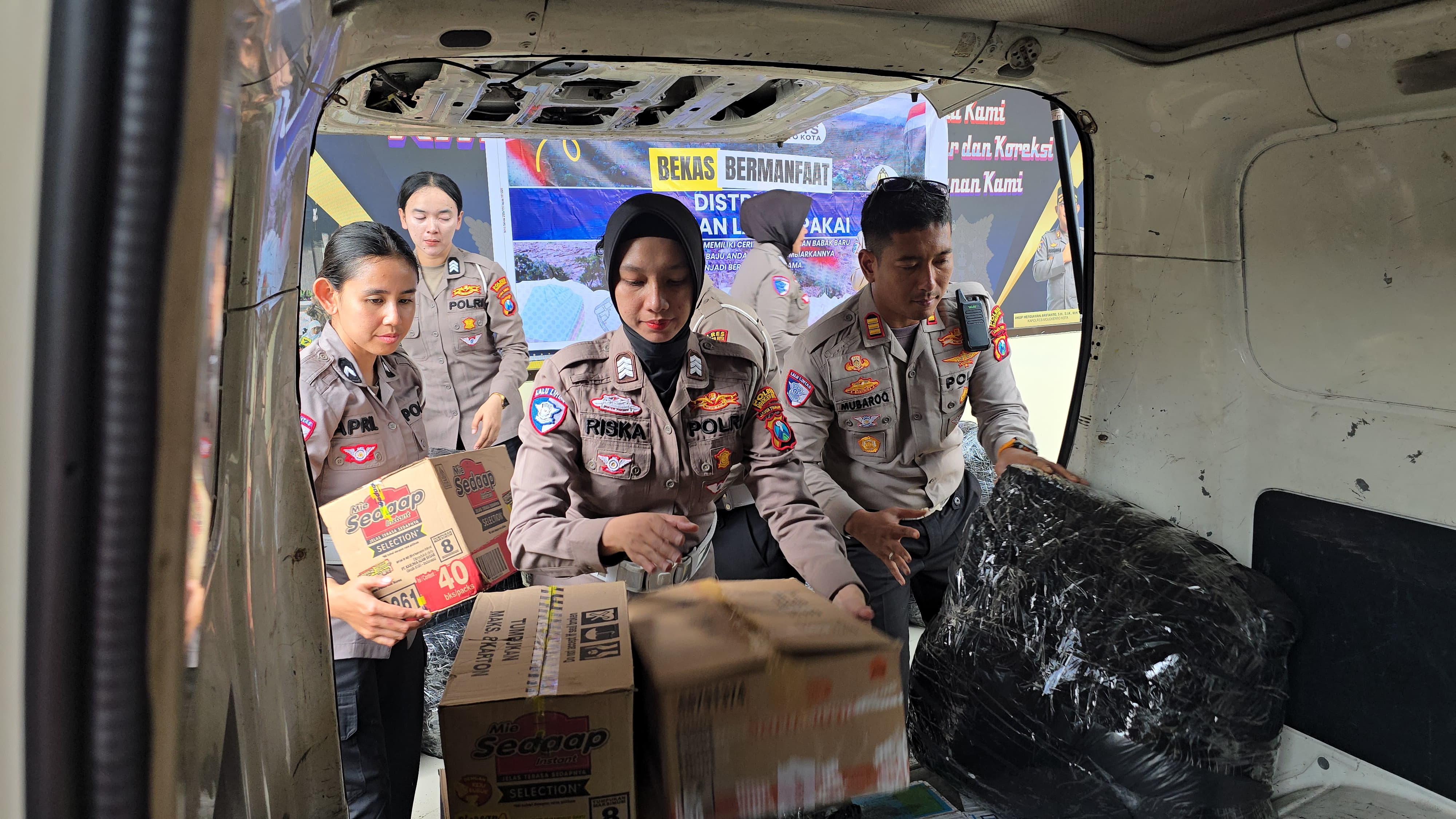 EMPATI: Petugas Satlantas Polres Mojokerto Kota memasukkan barang bantuan kemanusiaan bencana di Pulau Sumatera ke dalam mobil pengangkut paket di Mapolres, Selasa (9/12).