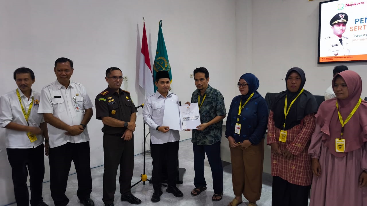 DUKUNGAN NYATA: Bupati Muhammad Albarraa didampingi Kadisperindag Noerhono bersama Kajari Kabupaten Mojokerto Fauzi (tengah) menyerahkan sertifikat halal kepada sejumlah pelaku IKM di aula kantor Keja