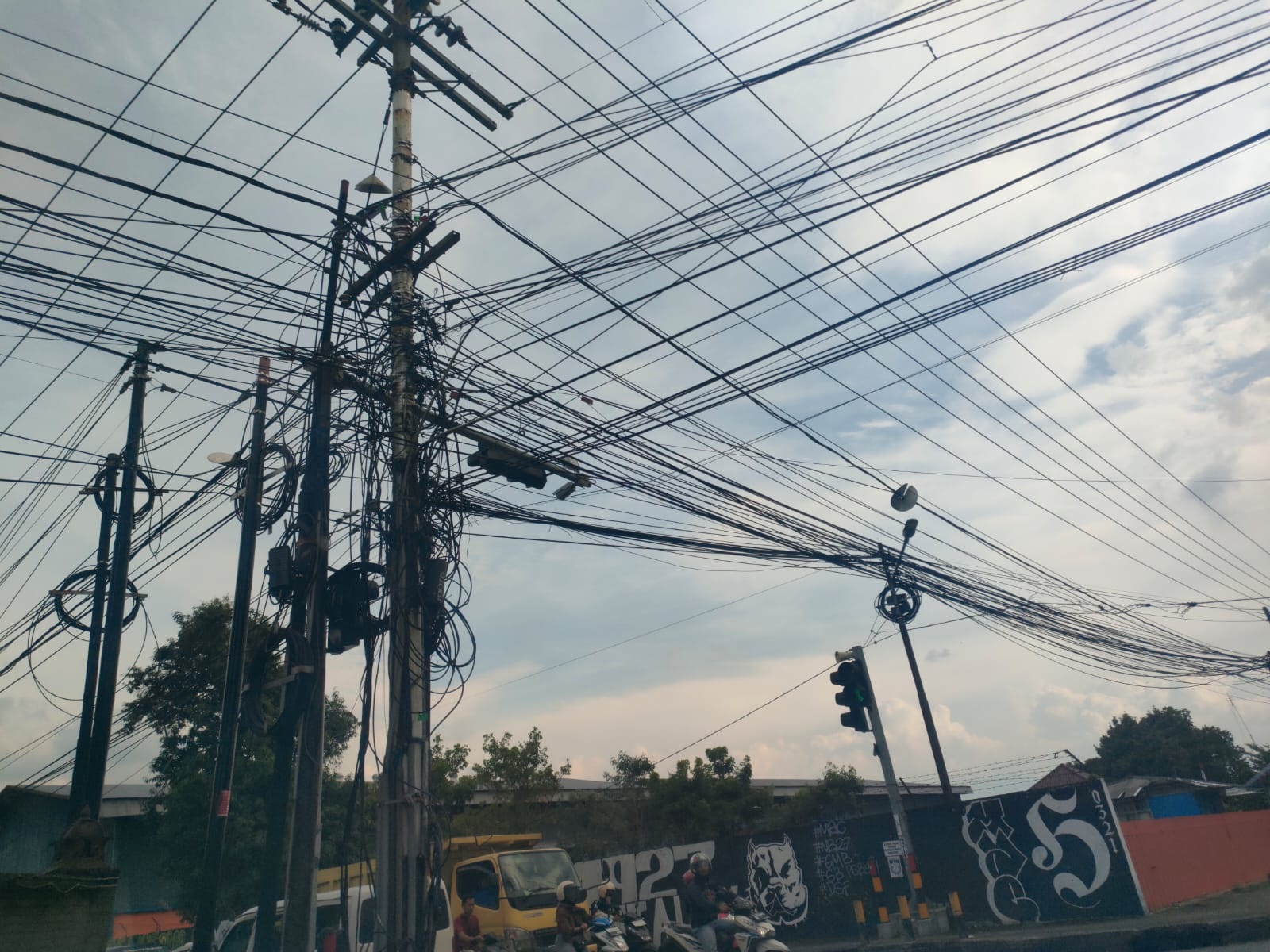 SEMRAWUT: Kondisi jaringan kabel FO milik beberapa provider yang memanfaatkan rumija di Jalan RA Basuni, Desa/Kecamatan Sooko. Belakangan pemkab akan melakukukan penertiban bagi yang kedapatan melangg