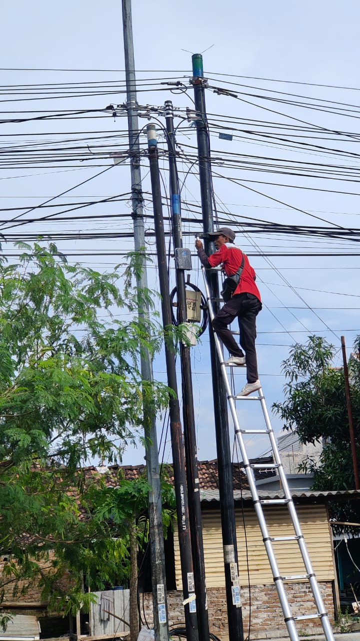 JADI SOROTAN: Salah satu teknisi provider melakukan pemasangan ODP pada tiang yang tak dilengkapi stiker kepatuhan retribusi di ruas Jalan Desa Banjaragung, Kecamatan Puri, kemarin (17/12).