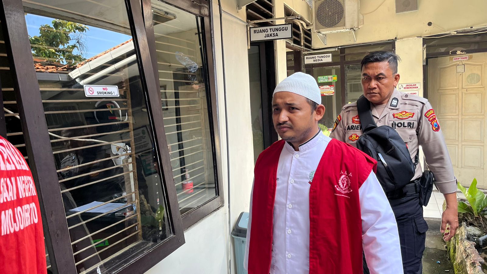 TEGA: MY, terdakwa kasus rudapaksa anak tiri saat digelendang petugas menuju ruang sidang Pengadilan Negeri Mojokerto, Rabu (17/12).