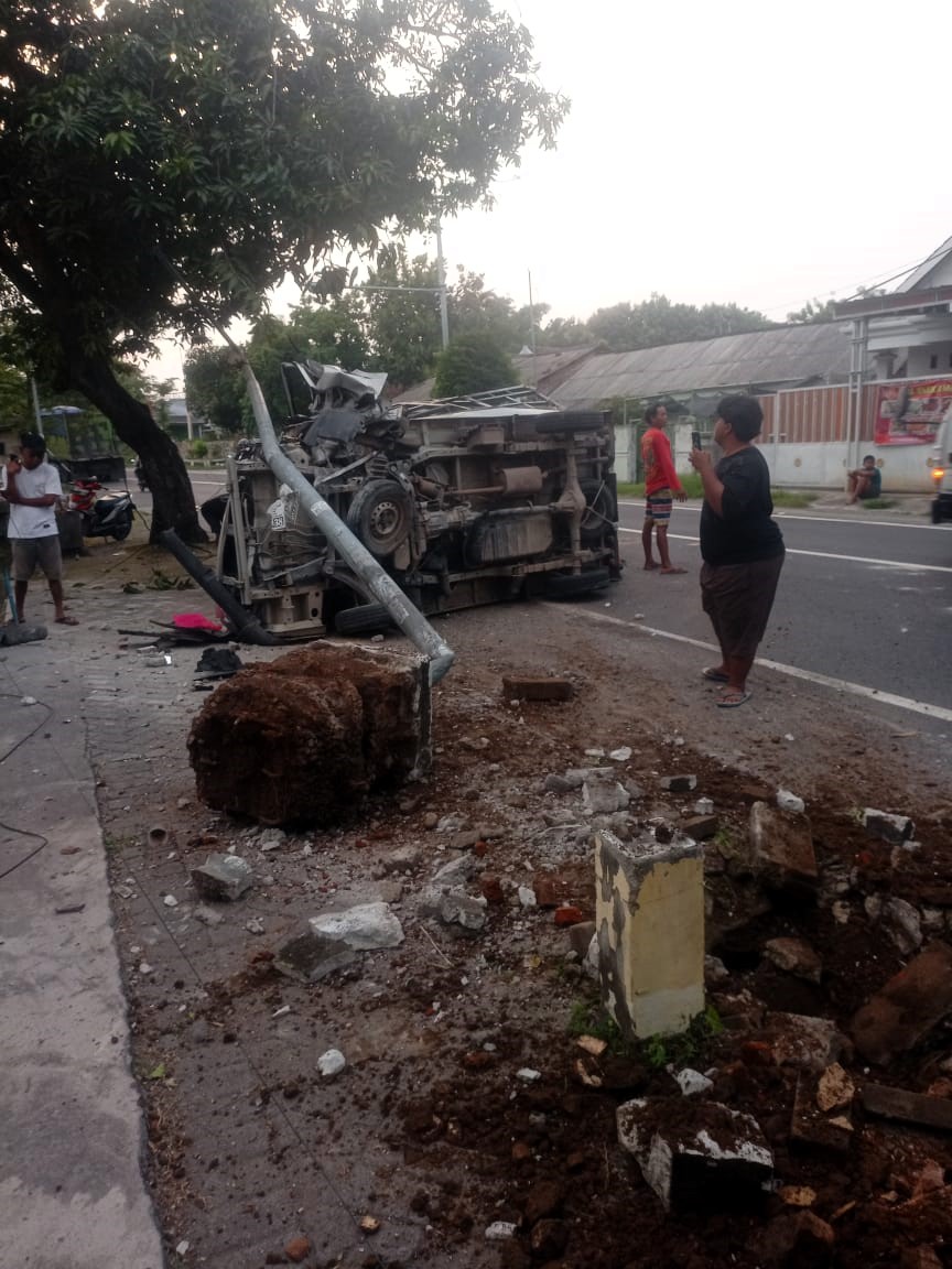 TERGULING: Pikap muatan bahan pakan ternak terguling usai mengalami kecelakaan tunggal di Jalan Raya Desa Betro, Kecamatan Kemlagi, Kamis (18/12) pagi.