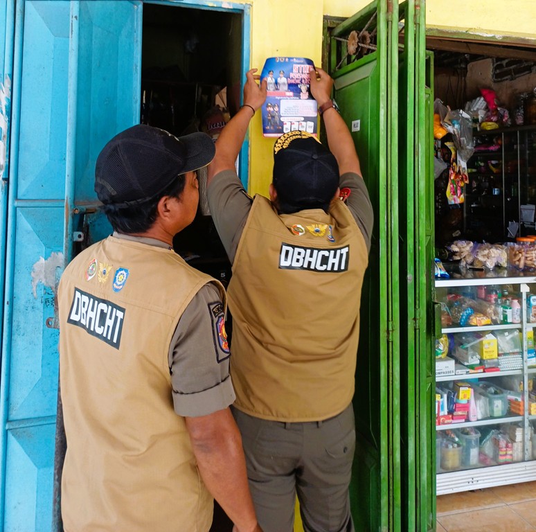 GEMPUR ROKOK ILEGAL: Petugas Satpol PP Kabupaten Mojokerto memasang stiker gempur rokok ilegal usai menggelar operasi di wilayah Kecamatan Pungging.