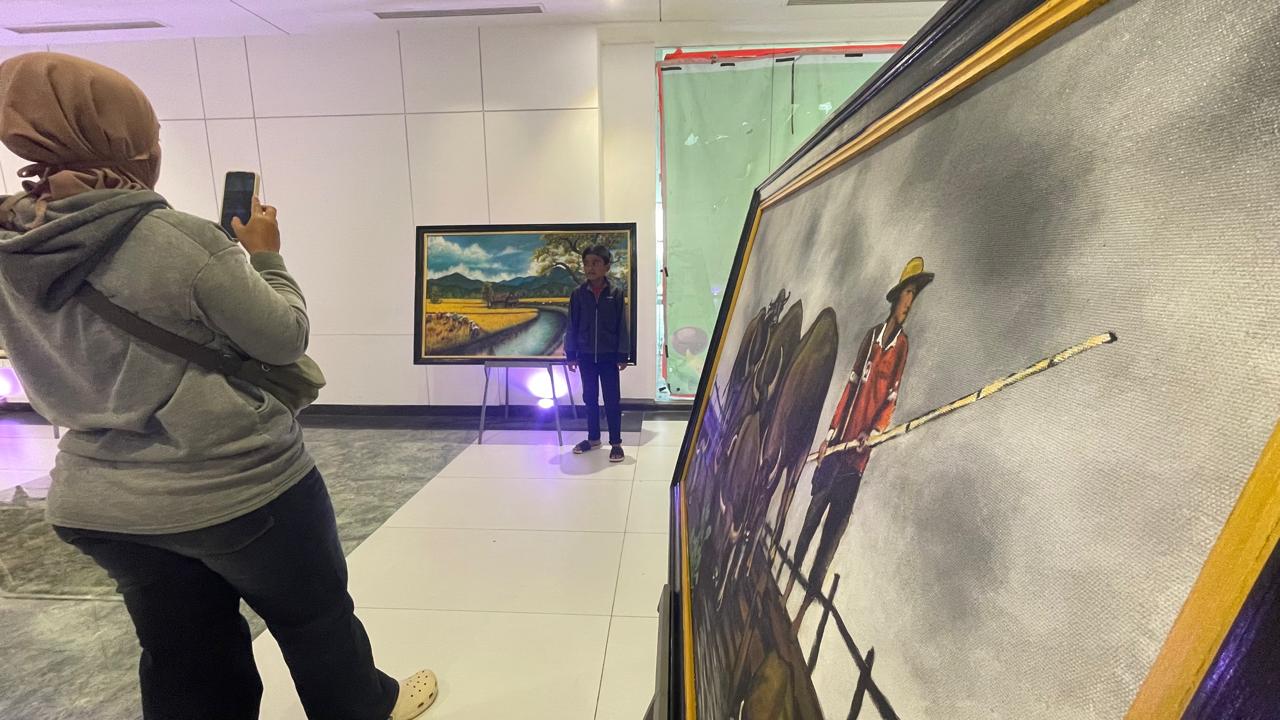 BEBAS BEREKSPRESI: Seorang pengunjung mengambil foto anaknya di depan lukisan karya Diak Eko yang dipajang dalam pameran tunggal event Gen Art di Sunrise Mall 2 Mojokerto, kemarin (23/12).