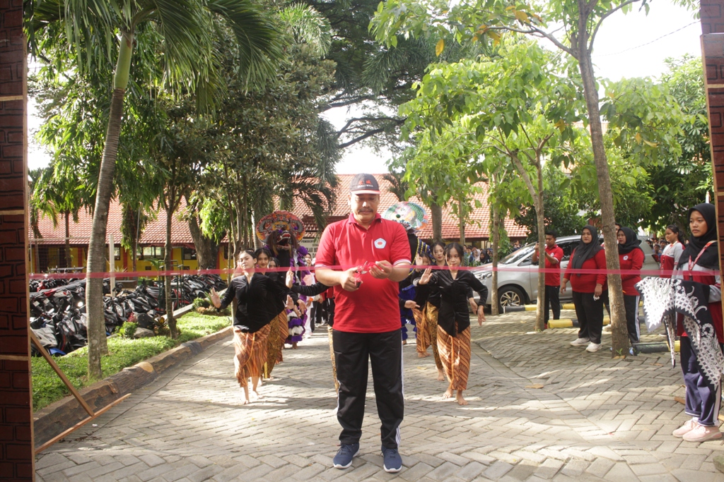 BERTAMBAH USIA: Kepala SMAN 1 Dawarblandong Edy Sucahyono memotong pita sebagai tanda diberangkatkannya peserta jalan sehat yang diikuti para siswa dan guru.