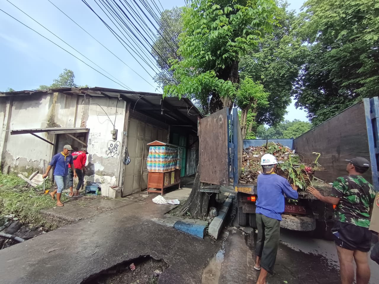 DITANGANI: Tim gabungan membersihkan material sampah yang menyumbat saluran air di Jalan Gajah Mada, Kecamatan Mojosari, kemarin (6/1).