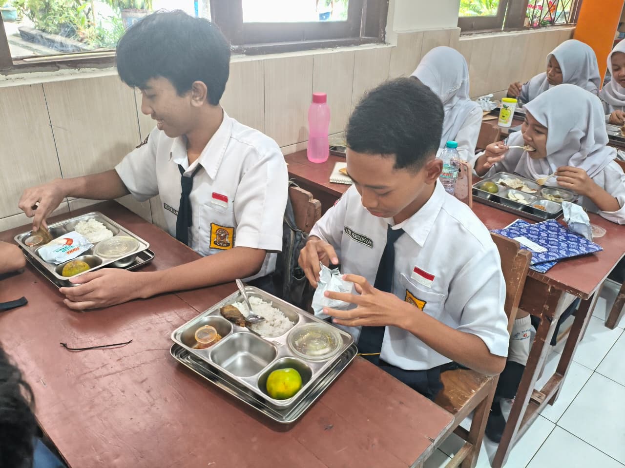 MENGIKUTI JADWAL: Siswa SMPN 6 Mojokerto baru menikmati paket program MBG yang telah didistribusikan perdana, Senin (5/1), usai operasional disetop bersamaan dengan libur semester ganjil.