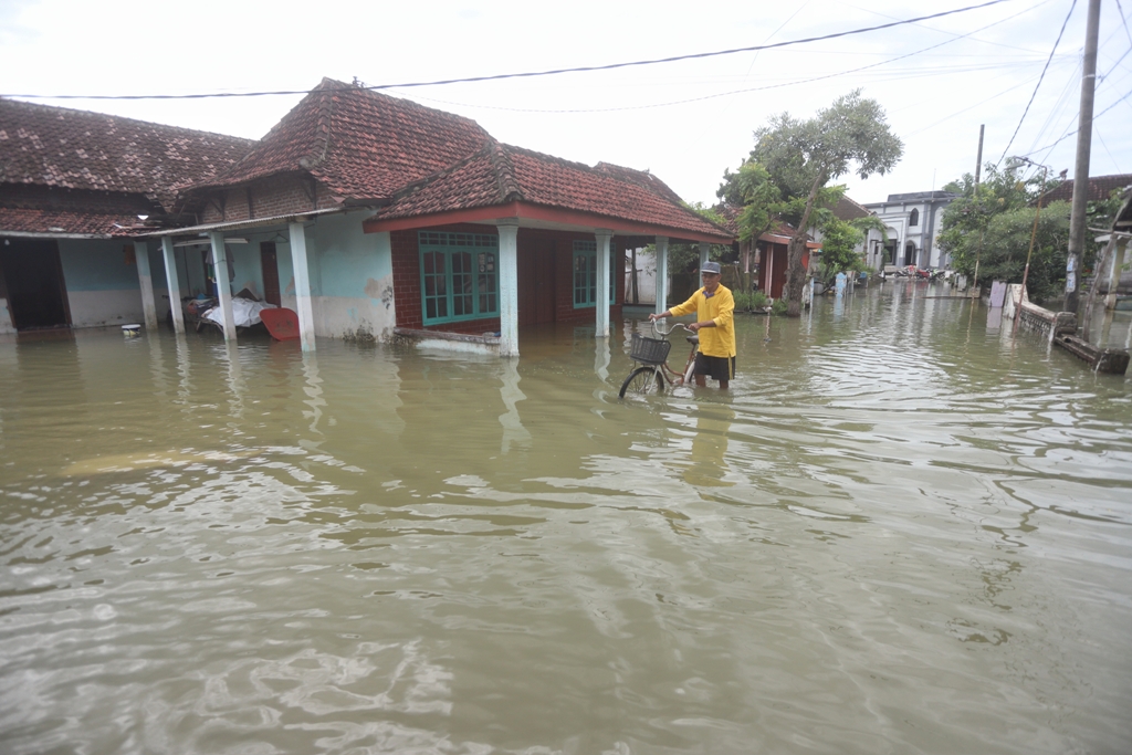LANGGANAN: Aktivitas warga Dusun Balong, Desa Banyulegi, Kecamatan Dawarblandong, di tengah banjir luapan Kali Lamong, kemarin (10/1).