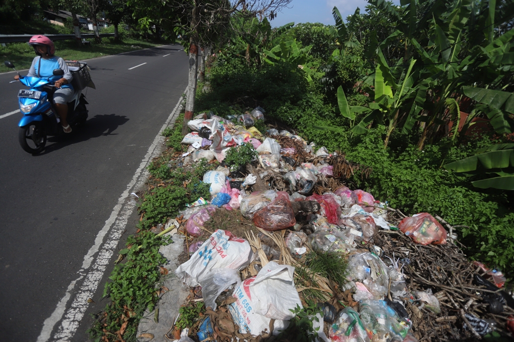 BAU BUSUK: Pengendara melintas di dekat tumpukan sampah di jalan Tropodo Kelurahan Meri, Kecamatan Kranggan, Kota Mojokerto Senin (19/1).