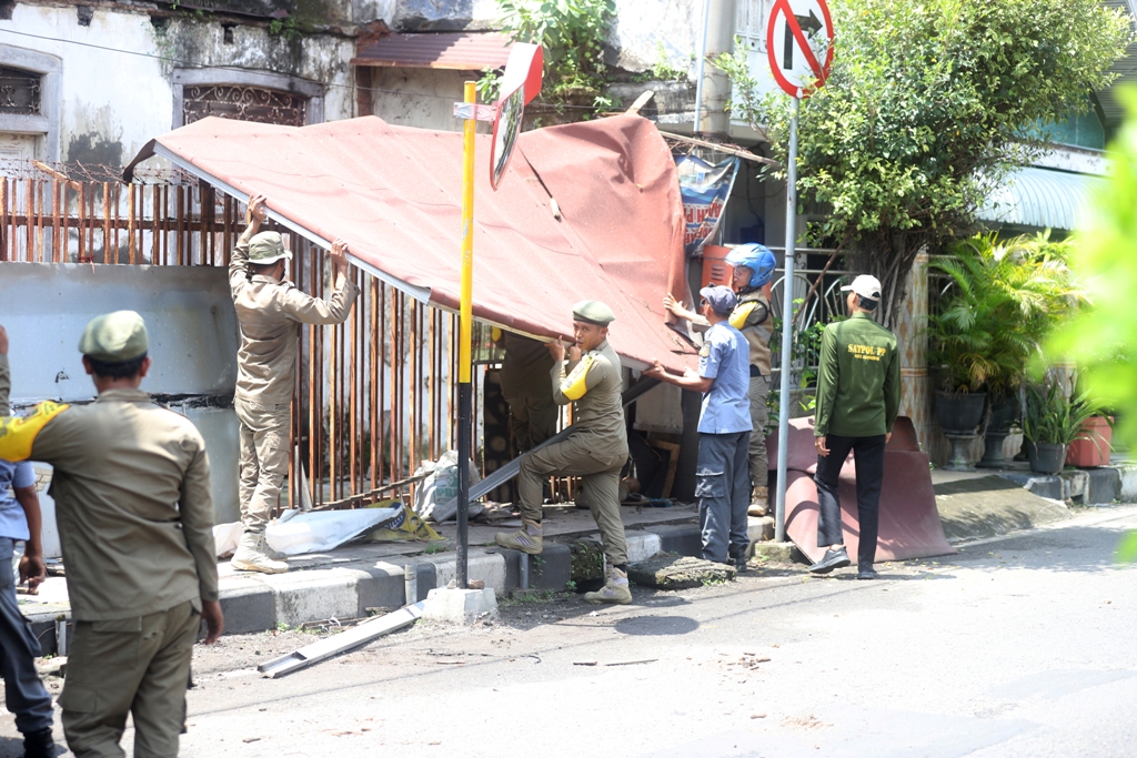 MEMBANDEL: Petugas Satpol PP membongkar bangunan lapak milik PKL dalam operasi penertiban yang digelar di Jalan Residen Pamudji kawasan Pasar Tanjung Anyar, Kota Mojokerto, kemarin (29/1).
