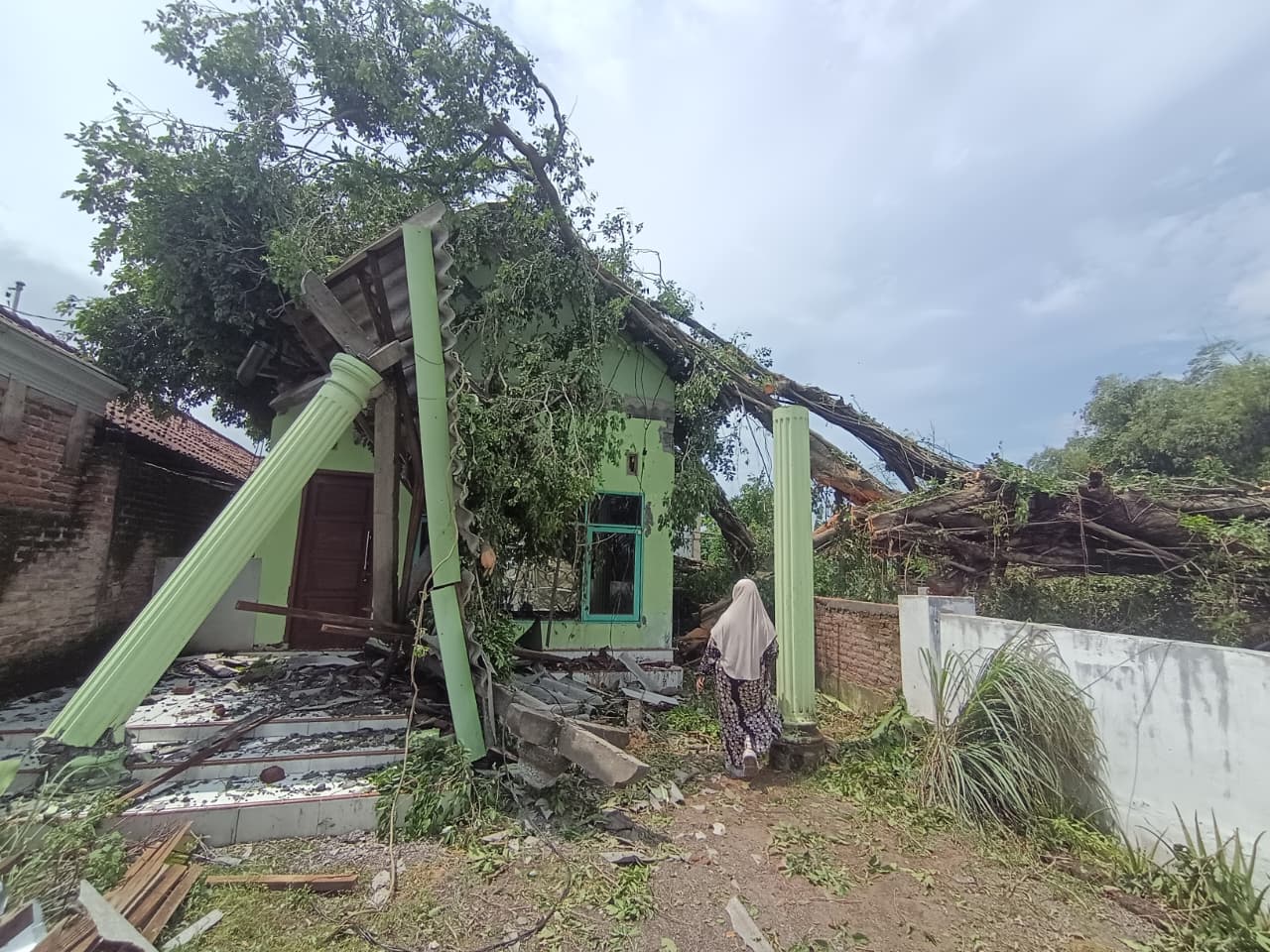 PORAK PORANDA: BPBD Kabupaten Mojokerto bersama relawan mengevakuasi pohon tumbang yang menimpa rumah warga di Dusun Panggreman, Desa Tunggalpager, Kecamatan Pungging, kemarin (1/2).