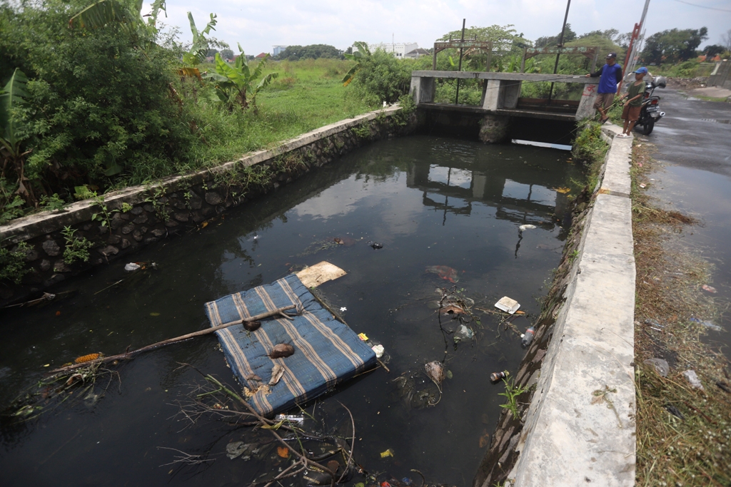 Ok-ris Foto // vad  KUMUH: Seorang pemotor melintasi Jalan Raya Blooto, Kelurahan Blooto, Kecamatan Prajurit Kulon, yang dijadikan lokasi pembuangan sampah liar, kemarin (8/2).