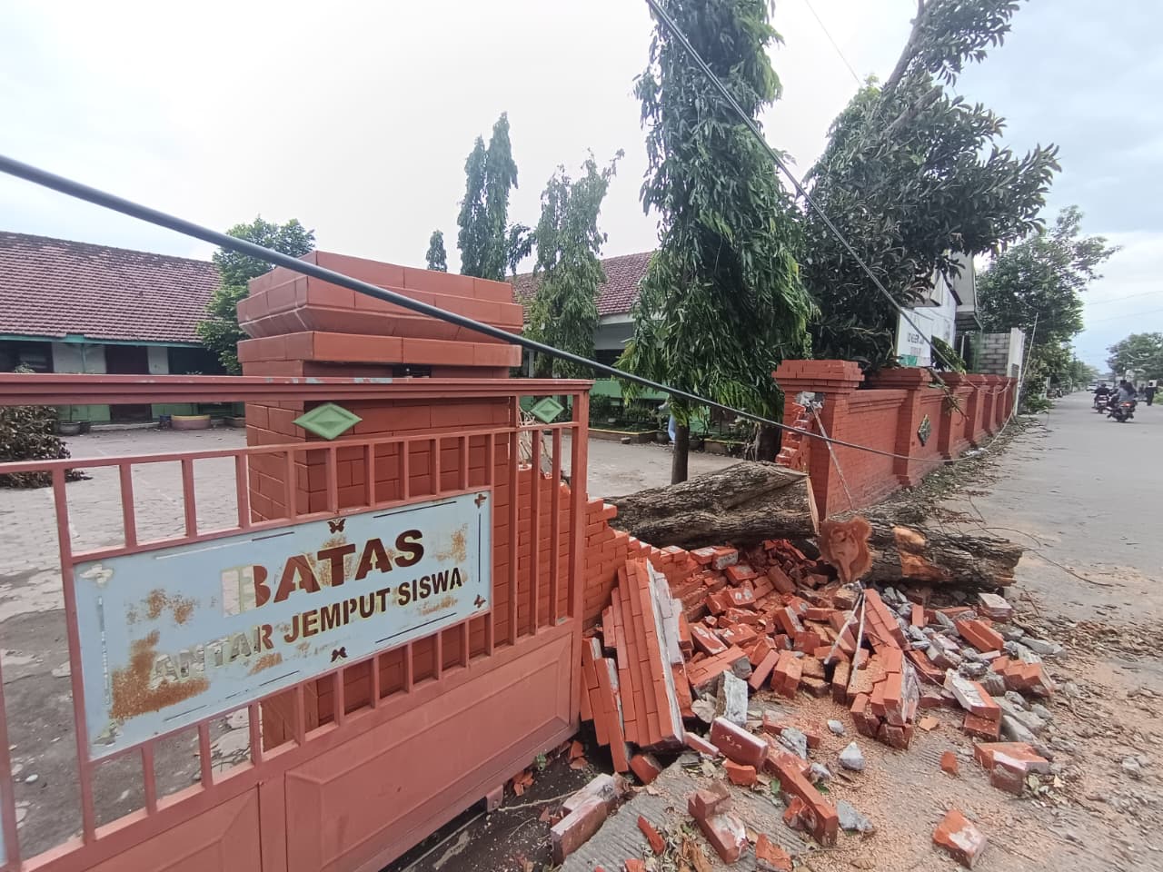 TERDAMPAK: Pagar SDN Jabon, Desa Jabontegal, Kecamatan Pungging, yang rusak tertimpa pohon tumbang akibat angin kencang, Sabtu (9/2).