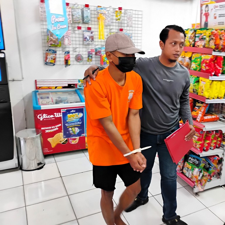 TAHANAN: Tersangka (mamakai baju tahanan) dikeler petugas ke gerai Alfamart Kedundung untuk melakoni rekonstruksi pencurian, Senin (16/2).