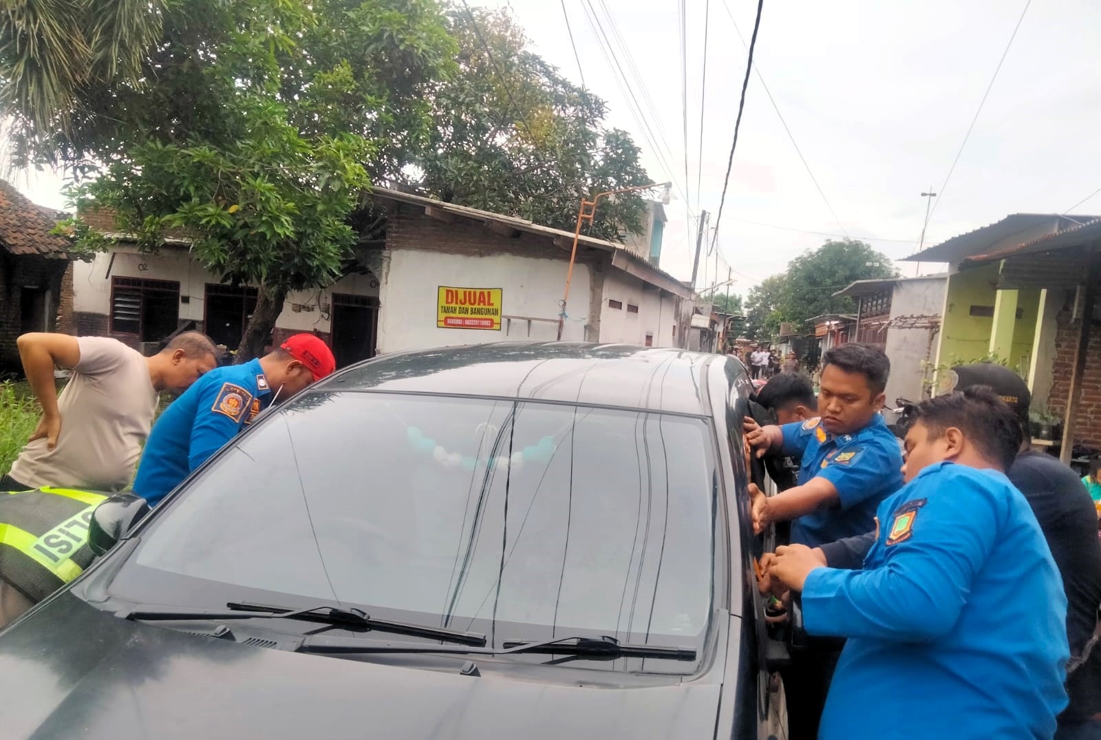 DRAMATIS: Petugas damkar berupaya membuka jendela mobil yang terkunci dari dalam, Selasa (17/2).