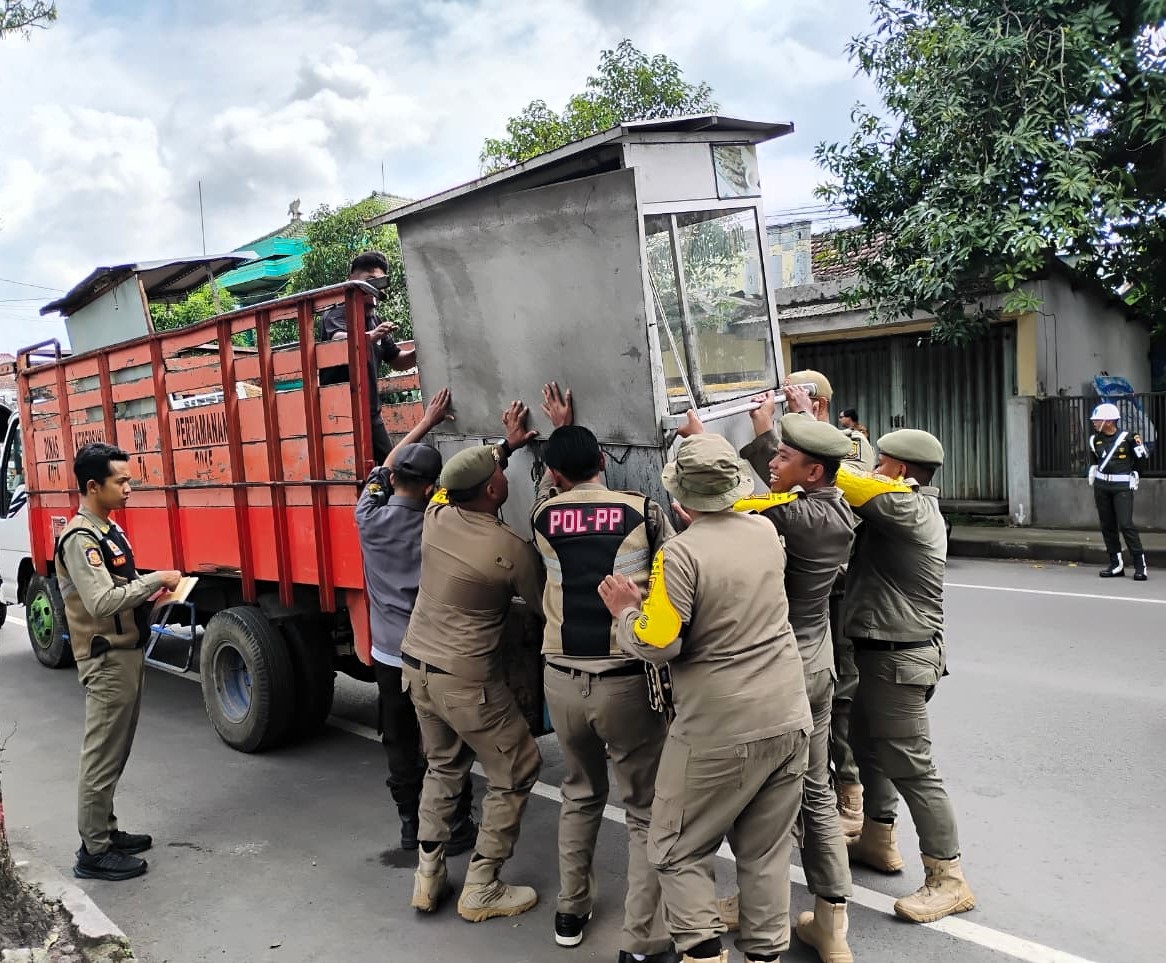 PILIH SLOW DOWN: Personel Satpol PP mengangkut rombong PKL yang terjaring razia di Jalan Raya Surodinawan, Kota Mojokerto, beberapa waktu lalu.