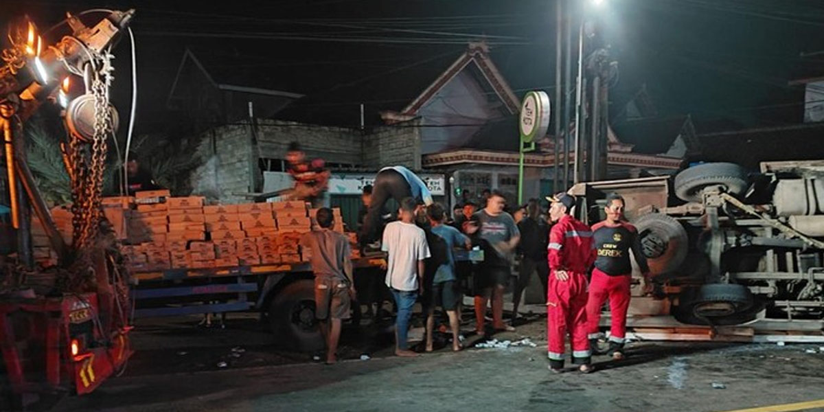 Warga mengambil susu yang berserakan usai truk terguling di Jetis, Ponorogo.