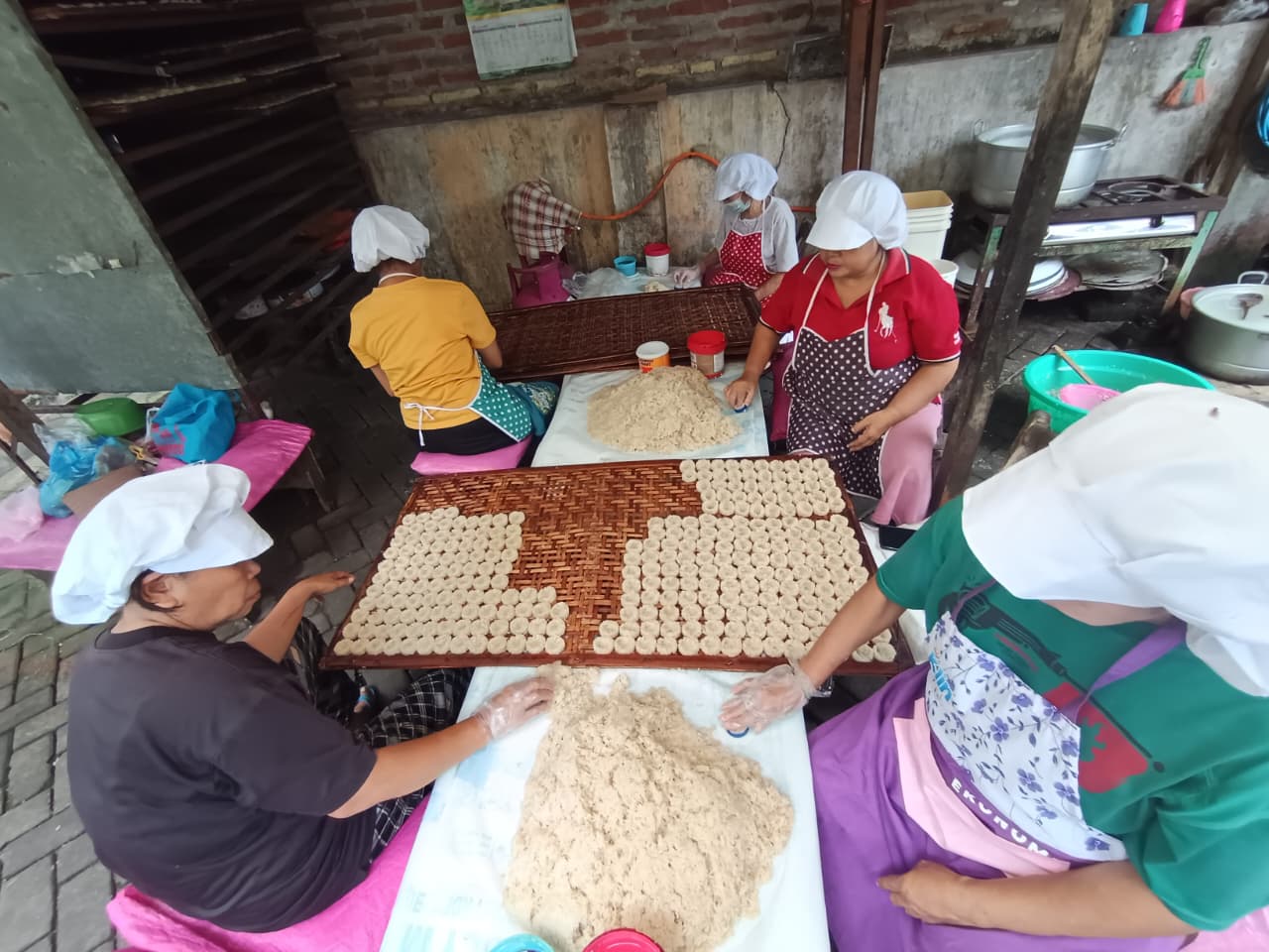 BERGELIAT: Pekerja di mengolah bahan baku beras ketan untuk diproses menjadi jajanan rengginang di Kelurahan Sawahan, Kecamatan Mojosari, Kabupaten Mojokerto.  