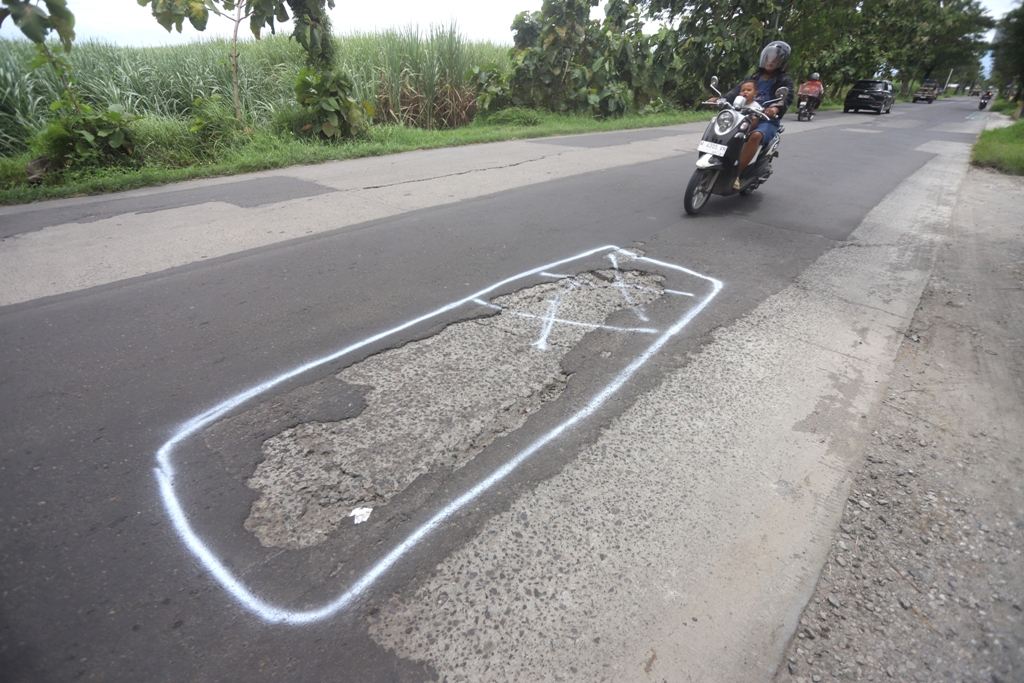 MENGANGA: Sejumlah lubang jalan tersebar di sepanjang ruas Ngabar-Dawarblandong, Kabupaten Mojokerto. Jalan kabupaten ini segera diperbaiki dinas PUPR sebelum masa mudik berlangsung.  