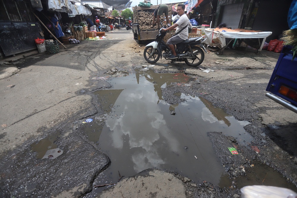 BECEK: Seorang pengendara roda dua melintasi jalan di area Pasar Tanjung Anyar Kota Mojokerto yang dipenuhi kubangan air, Kamis (5/3).