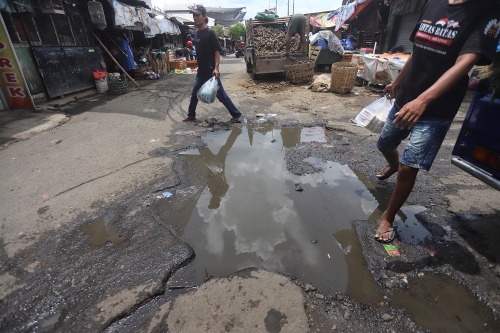 Pengunjung Pasar Tanjung Anyar Kota Mojokerto menghindari kubangan air di jalan setempat, Kamis (5/3).