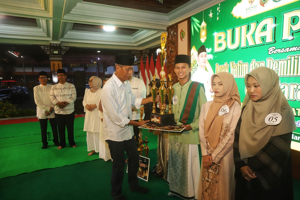 APRESIASI: Direktur Jawa Pos Radar Mojokerto M. Nur Kholis memberikan tropi juara kedua Pildarama 2026 kepada M. Hazza Rahid Alfayi dari MTSN 1 Mojokerto.  