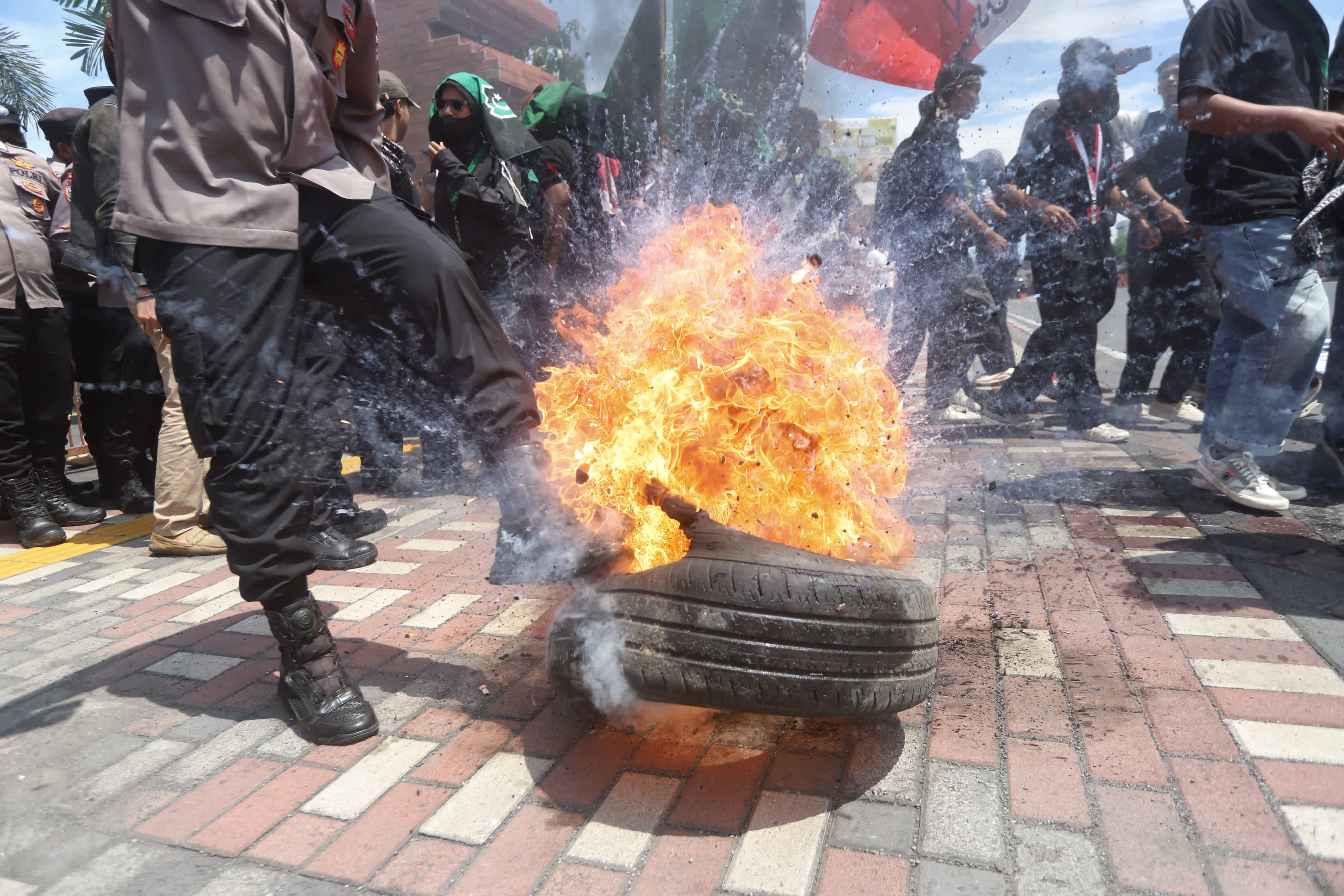PICU RICUH: Seorang polisi menendang ban yang terbakar di depan massa aksi demo depan Balai Kota Mojokerto Jalan Gajah Mada, Kota Mojokerto, Rabu (11/3). 