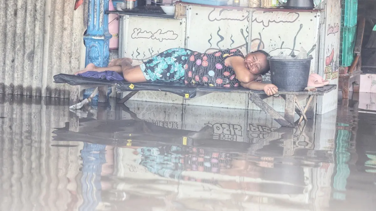 DIGENANGI BANJIR: Seorang warga Dusun Gembongan, Desa Jotangan, Kecamatan Mojosari, Kabupaten Mojokerto bersantai di depan warungnya, Senin (16/3). Ratusan rumah warga setempat digenangi banjir luapan Kali Sadar. 
