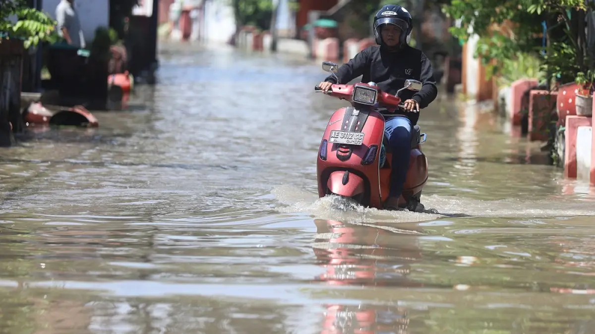 MASIH TERGENANG: Warga melintasi jalan perkampungan di Dusun Gembongan, Desa Jotangan, Kecamatan Mojosari, Kabupaten Mojokerto yang masih terendam air, kemarin (17/3). (Sofan Radar Mojokerto)