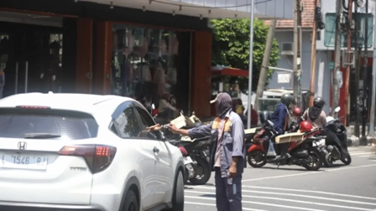 DISOROT WARGA: Seorang tukang parkir menerima pembayaran di ruas Jalan Mojopahit, Senin (6/4) lalu. Program parkir berlangganan yang diterapkan Pemkot Mojokerto menuai sorotan warga karena kerap kali di lapangan pembayaran dilakukan dua kali. (Sofan JPRM)