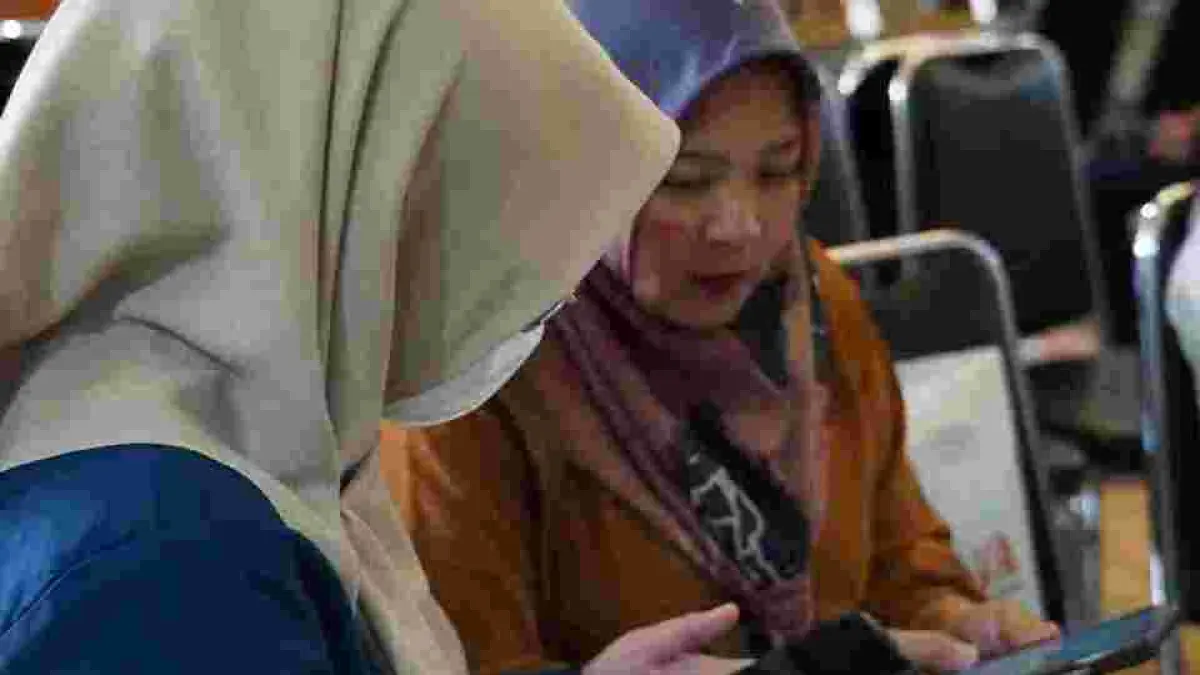 Petugas BPJS Kesehatan membantu proses layanan kepada pengunjung yang datang ke kantor. 