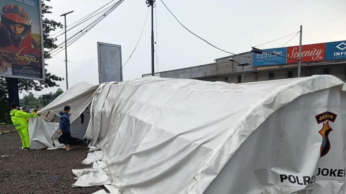 ROBOH: Personel Polres Mojokerto mengevakuasi tenda pos pengamanan yang ambruk diterjang angin kencang di simpang 5 Kenanten, Kecamatan Puri, kemarin (12/4). (Rizal JPRM)