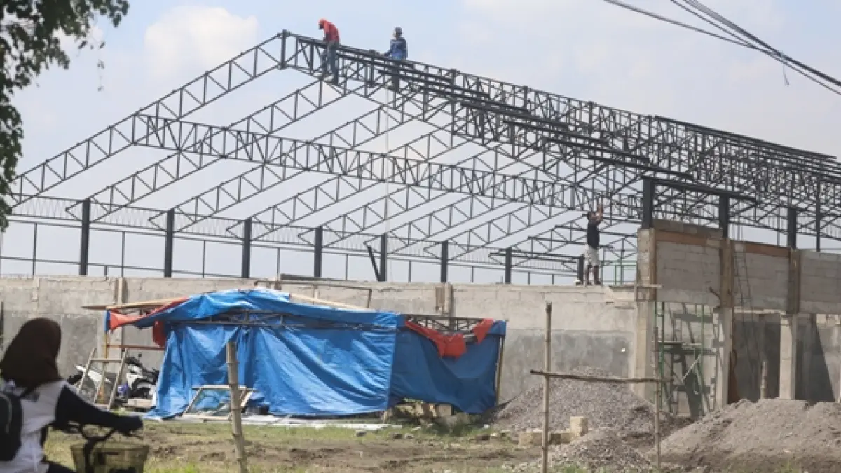 PENUH RISIKO: Sejumlah pekerja pembangunan proyek KDMP di Desa Ngabar, Kecamatan Jetis, Kabupaten Mojokerto, memanjat rangka atap baja tanpa menggunakan alat pengaman diri yang memadai, Jumat (17/4). (Sofan JPRM)