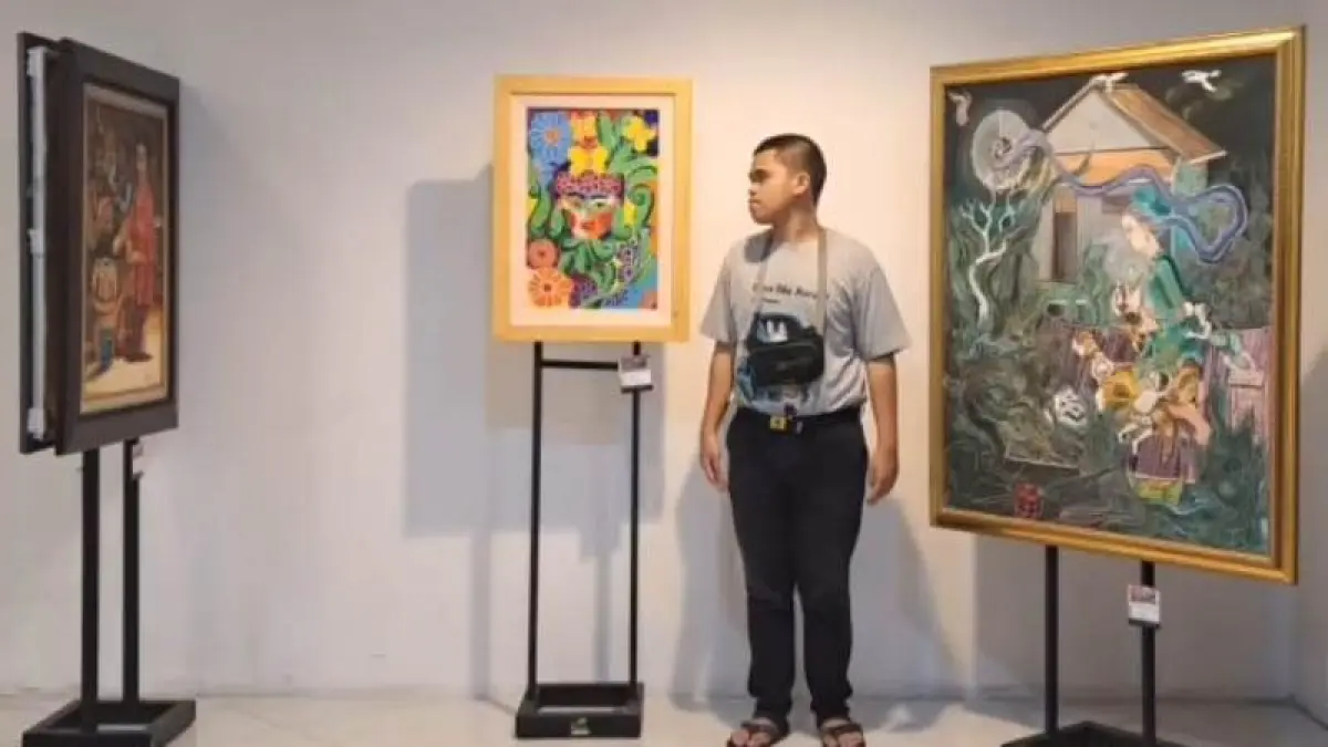 PELUKIS DIFABEL: Dani ketika menunjukkan karyanya yang dipajang di Pameran Rupa Karya Nusantara di The Central Mall Gunawangsa, Surabaya, Sabtu (25/4). (dok Priyok for JPRM)