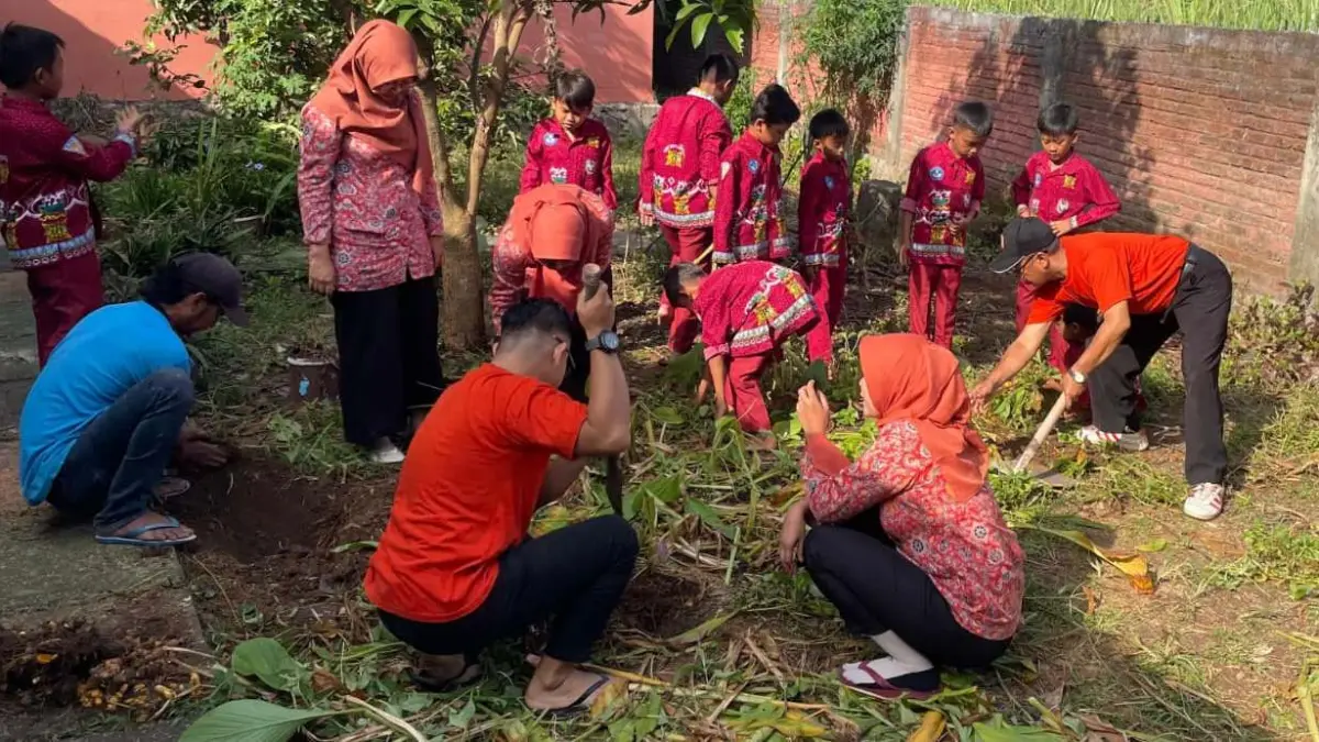 PELESTARIAN: Kepala SDN Trowulan Sakuwan bersama siswa dan guru gotong royong melakukan proses penggilingan sampah daun untuk kompos. (Oce JPRM)