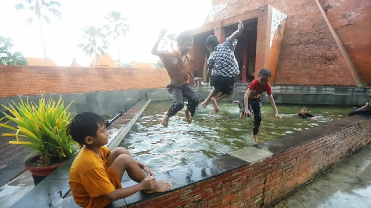 FASILITAS UMUM: Sejumlah anak memanfaatkan kolam hias di bawah menara Alun-Alun Wiraraja Kota Mojokerto sebagai kolam renang dadakan. Meski air keruh dan kotor, anak-anak berenang di tengah cuaca siang yang terik, Jumat (1/5). (Sofan JPRM)