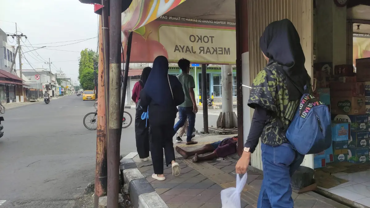 KELELERAN: Pejalan kaki melintas menghindari seorang ODGJ yang tiduran di depan toko Jalan Mojopahit, Kota Mojokerto. (Arief JPRM)